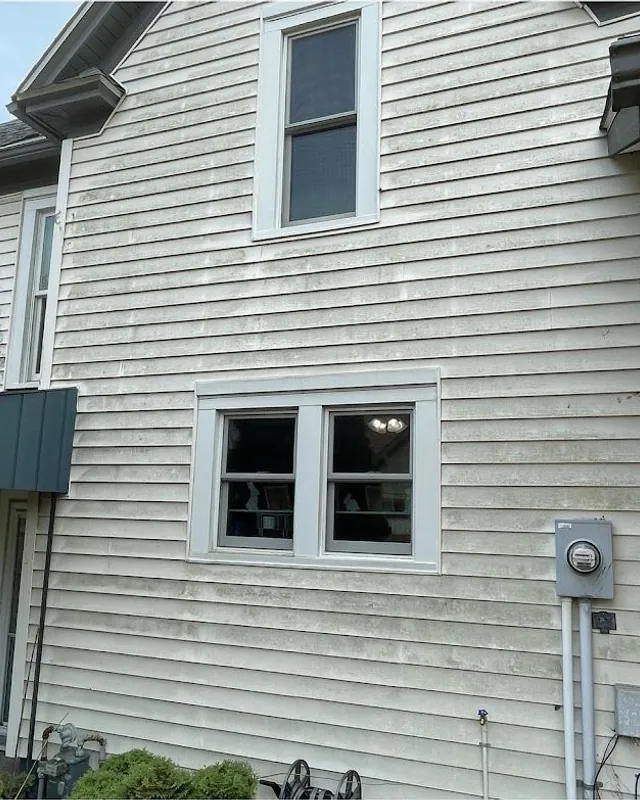 A full side of white siding with dirt and staining before washing