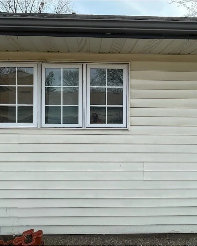 White siding below three windows, dirty before washing