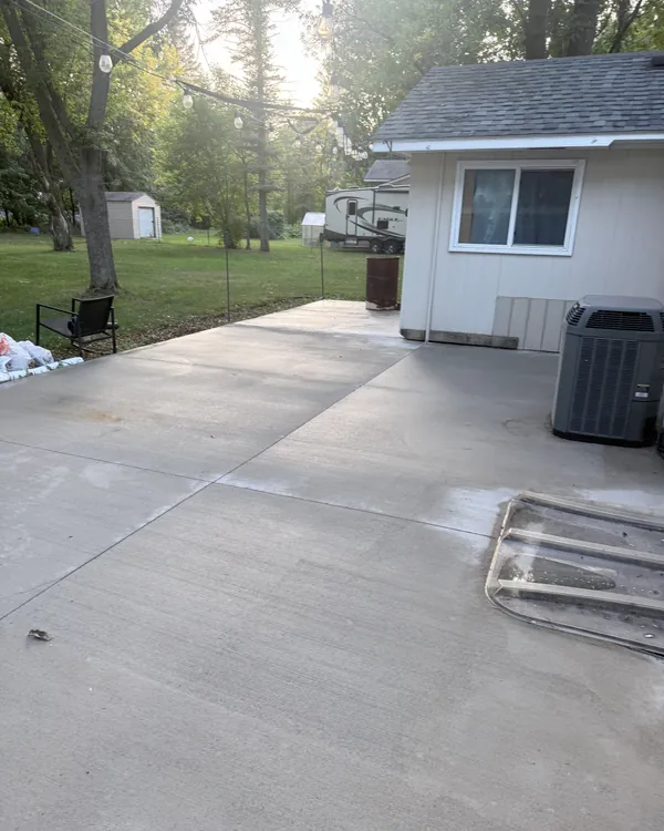 The same concrete patio clean and wet after pressure washing