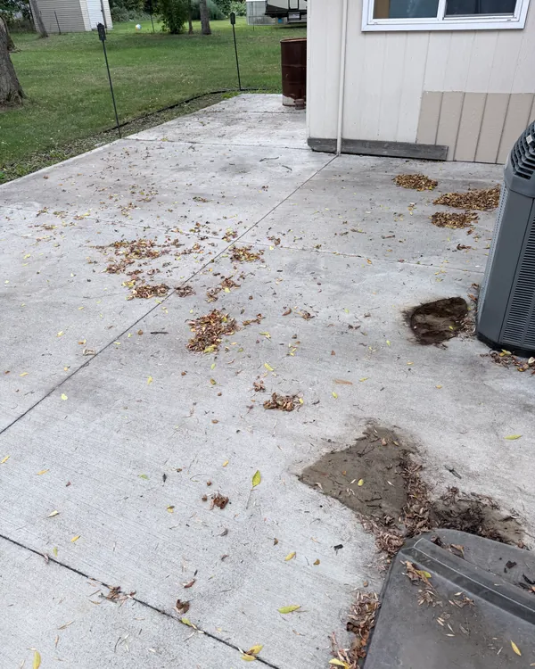 Concrete patio covered in leaves and dirt before pressure washing