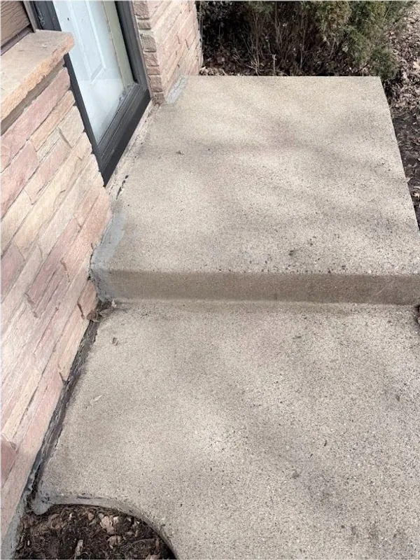 Clean concrete step and walk beside a brick wall